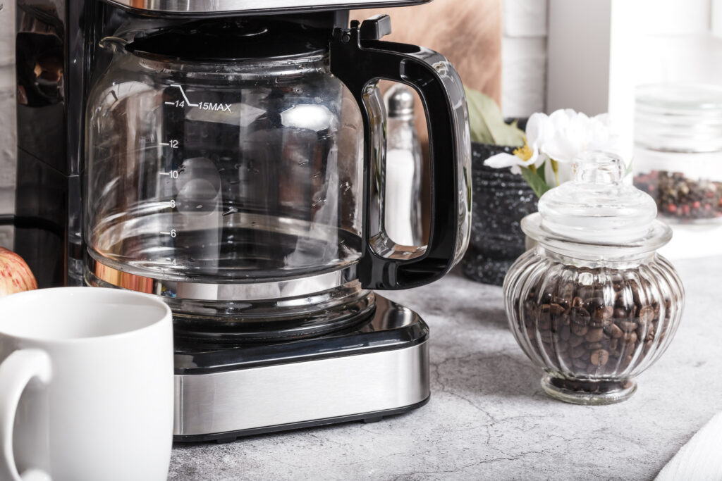 A drip coffee maker next to a jar of coffee beans.