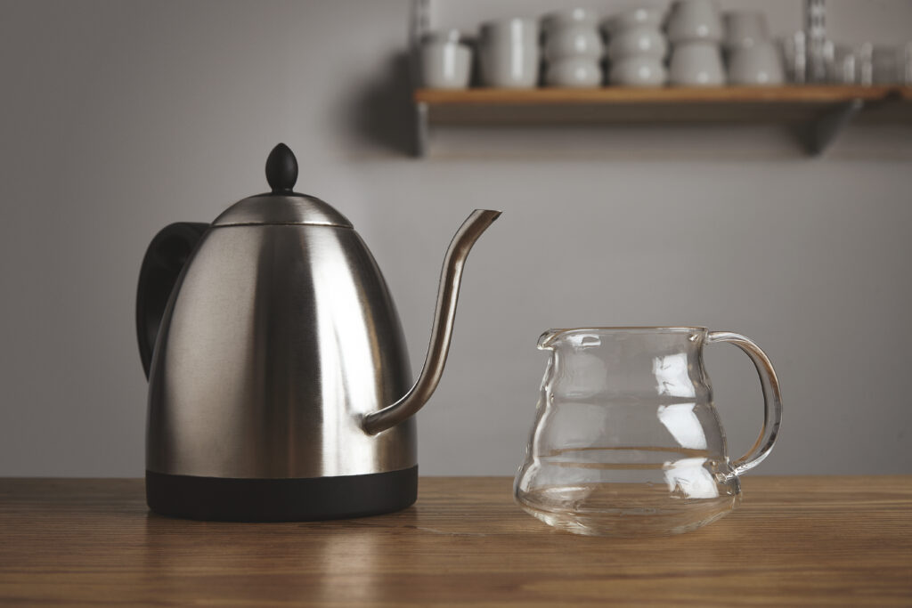A kettle and glass carafe on a table.