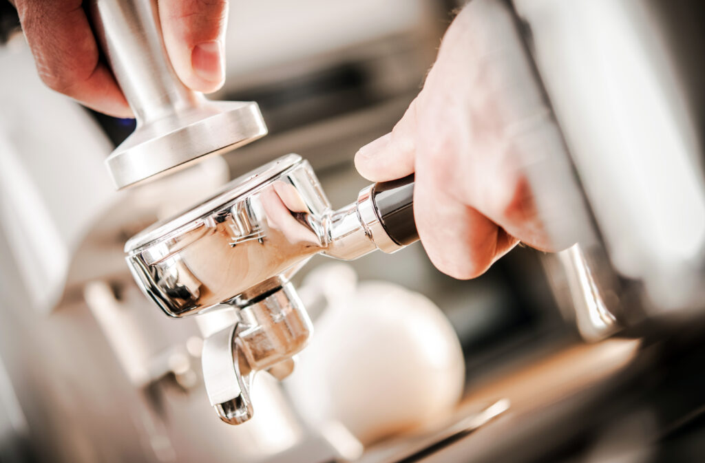 Caucasian Barista Preparing Espresso A barista tamping an espresso puck.