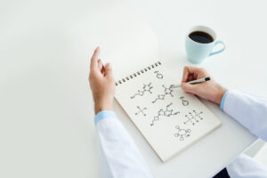 A notebook with molecular diagrams next to a cup of coffee.