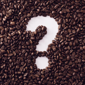 A question mark made with the white space in a pile of coffee beans.